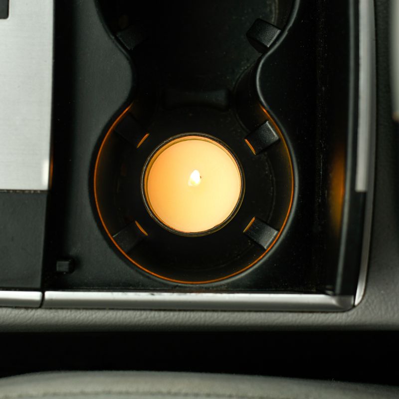 Lit Votive candle sitting in a car's cupholder