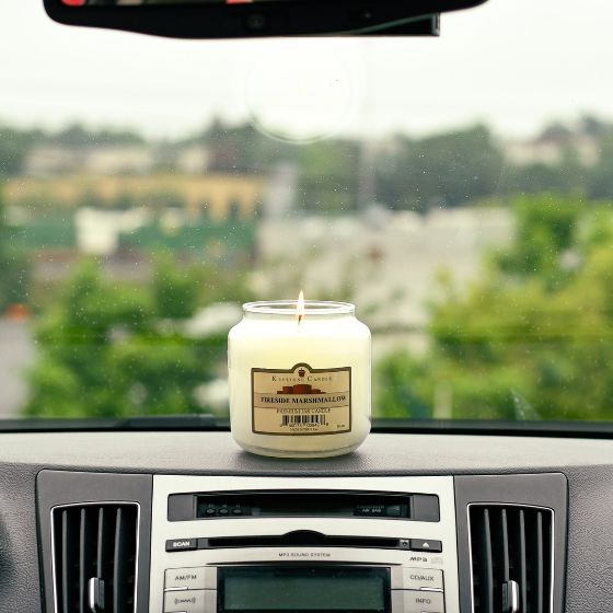 Lit 16-ounce candle sitting on a car's dashboard
