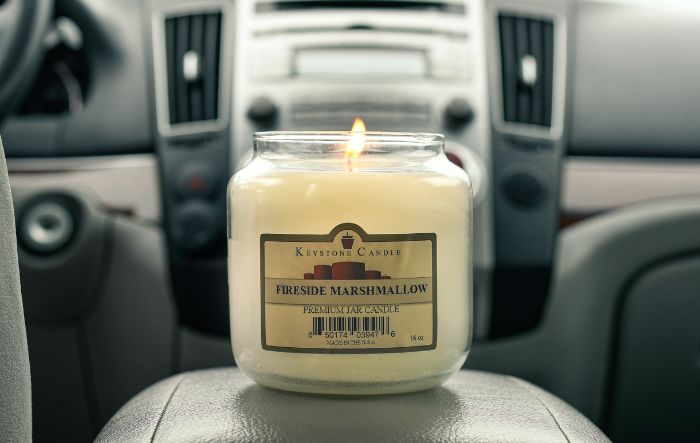 Lit 16-ounce candle sitting on the center console of a car