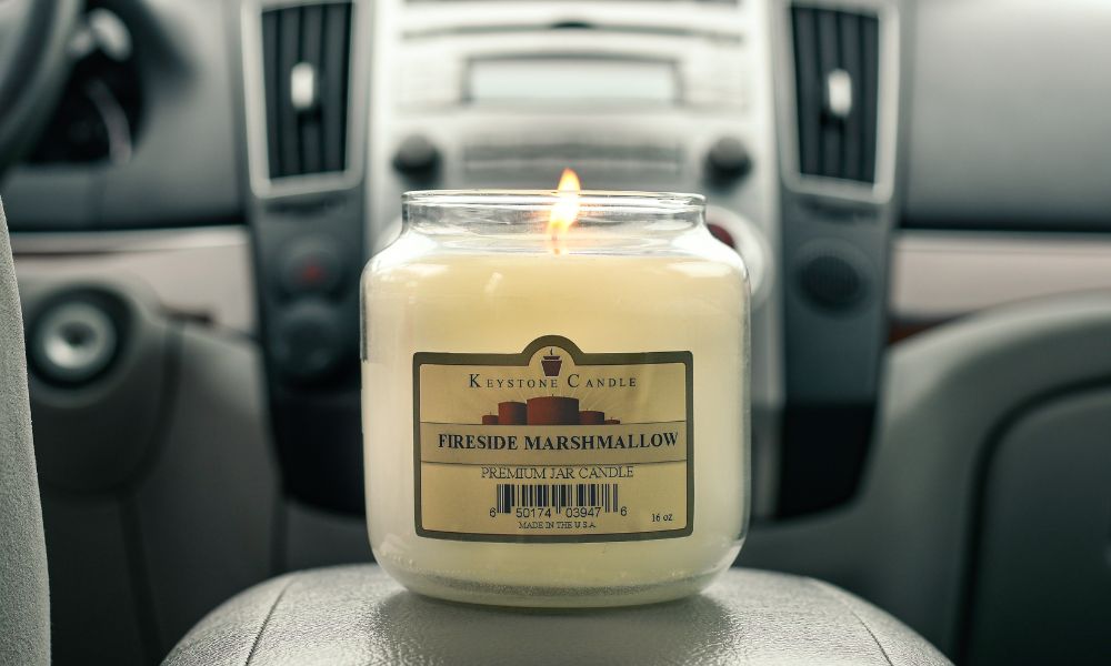 Lit 16-ounce candle sitting on the center console of a car