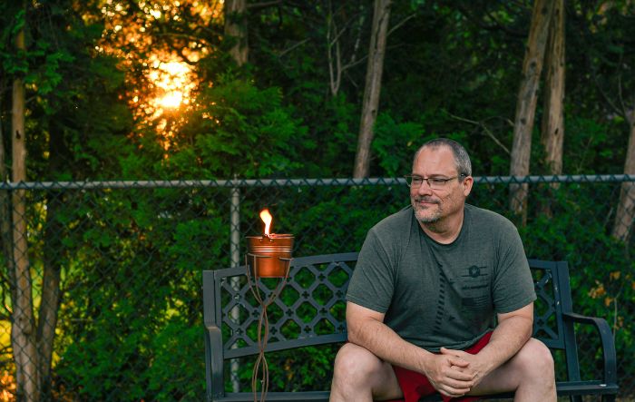 Man sitting outside next to a citronella bucket candle